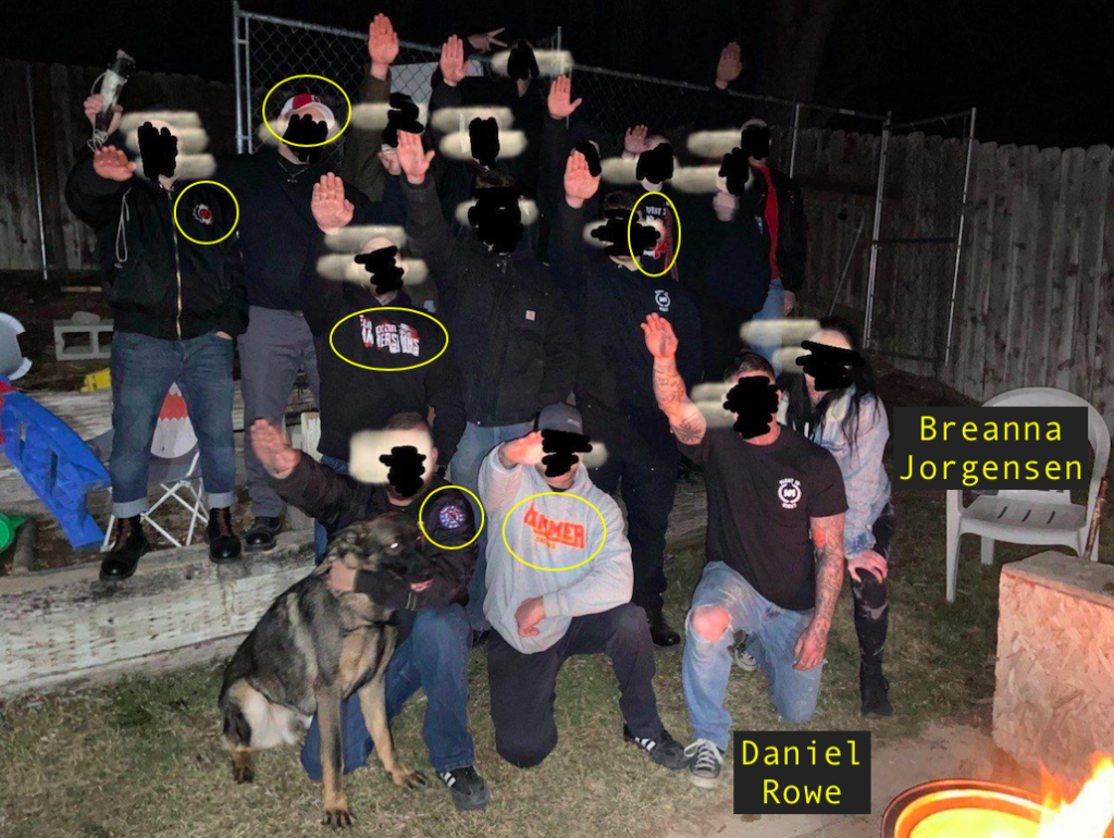 a group of hammerskin nazis with their faces blurred, doing the roman salute for the camera. there are six visible hammerskins logos on peoples clothing, which are circled. daniel rowe and breanna jorgensen are labeled.