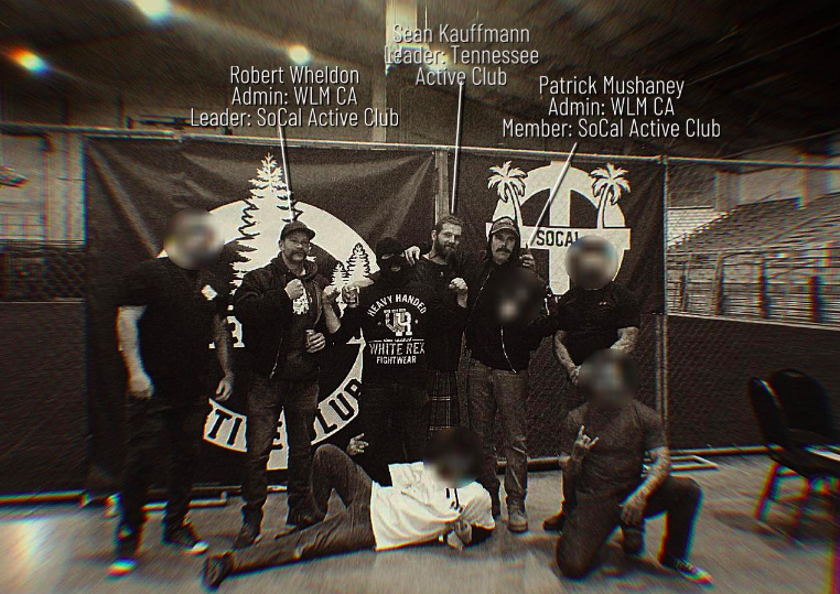 B&W image showing the Martyrs Day Rumble in Pasco. 8 men, mostly with blurred faces, are standing in front of active club flags. Three are not blurred, and they are labeled Robert Wheldon (SoCal AC), Sean Kauffmann (Tennessee AC) and Patrick Mushaney (SoCalAC)