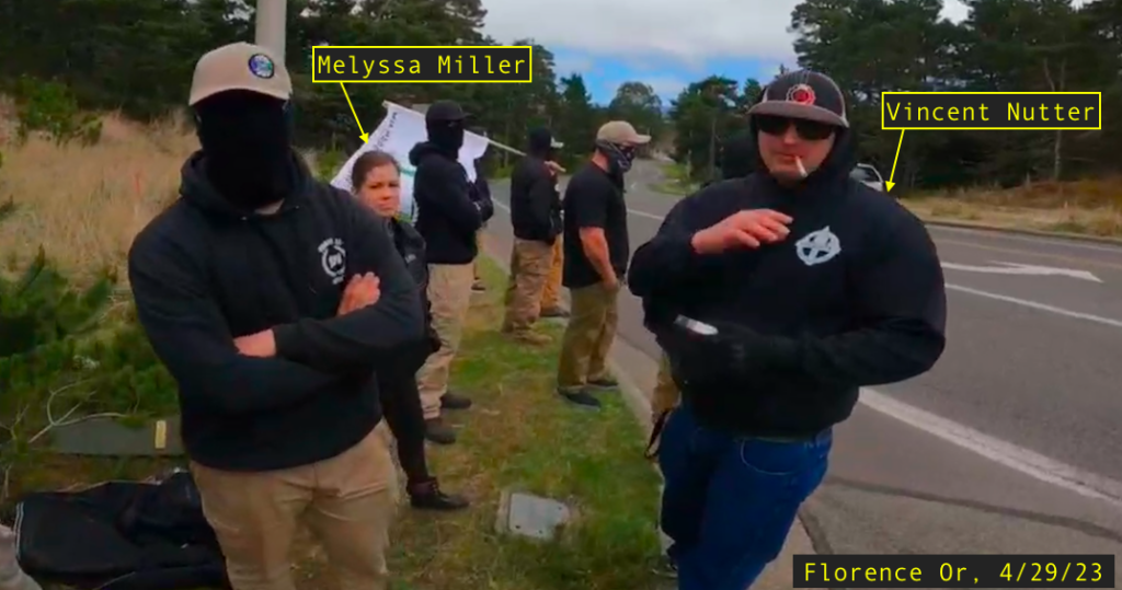 a group of people standing on the side of the road. Most of them have their faces covered. They are wearing black hoodies that say Might is Right. Vincent Nutter is wearing an EAC hoodie and Hammerskins baseball hat. Him and Melyssa Miller are labeled in the photo, taken on 4/29/23 in Florence