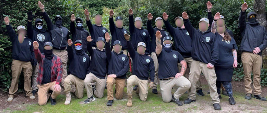 About twenty nazis pose for a group photo, all doing nazi salutes. 