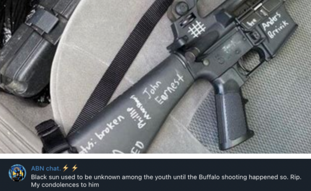 Two photos one on top of the other. The top photo is of a black rifle with words written in white paint pen. There is a St.Michael's Cross written on the upper receiver. 

The bottom is a screenshot from the ABN chat. Says "Black sun used to be unknown among the youth until the Buffalo shooting happened so. Rip. My condolences to him."