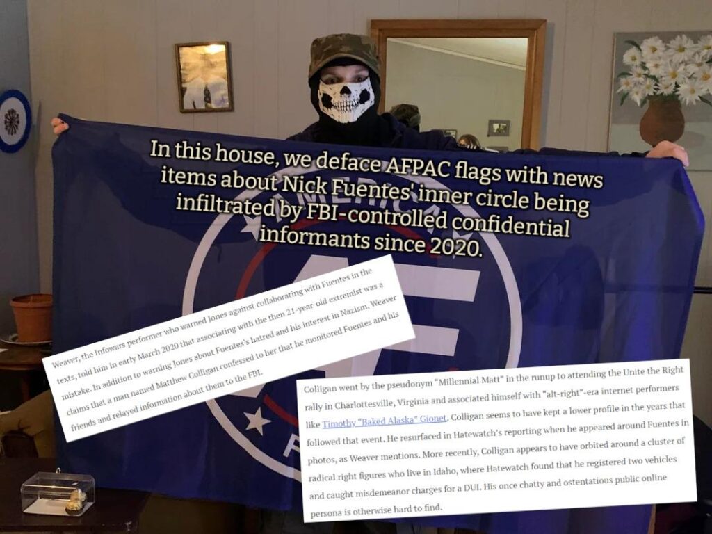 Ian is wearing a skull mask and holding up the America First flag of the Groypers. Over the flag is written, "In this house we deface AFPAC flags with news items about Nick Fuentes' inner-circle being infiltrated by FBI-controlled confidential informants since 2020." A couple screens of news clips also cover the flag. In the mirror behind Ian you can see just the top of what appears to be a woman's head as she takes the picture.